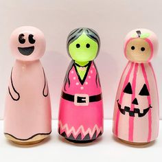 three wooden dolls are painted pink and green