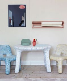 two children's chairs and table in a room with white walls, wood flooring and artwork on the wall