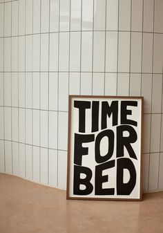 a black and white poster with the words time for bed on it in front of a tiled wall