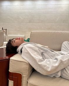 a person laying on top of a couch next to a table