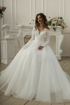 a woman in a white wedding dress sitting on a chair with her hands on her hips