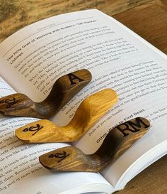 three wooden spoons sitting on top of an open book with numbers carved into them