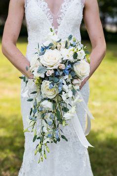 a bride holding a bouquet of white and blue flowers