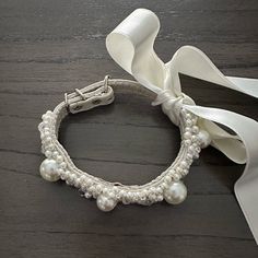 a close up of a bracelet on a table with a white ribbon and some beads