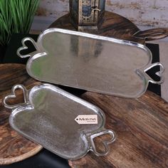 two metal trays sitting on top of a wooden table