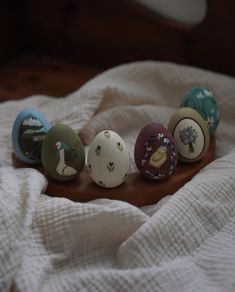 five ceramic eggs sitting on top of a bed