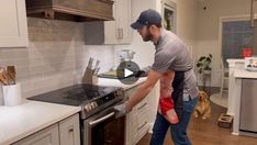 a man holding a baby in his arms while standing next to an open stove top oven