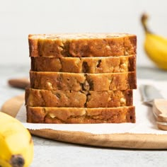 four slices of banana bread sitting on top of a cutting board next to some bananas