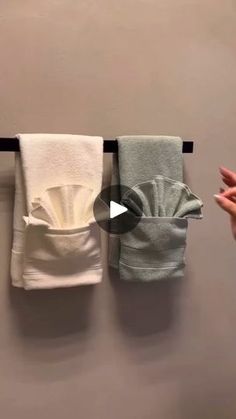 three towels hanging on a wall with one folded in half and the other rolled up