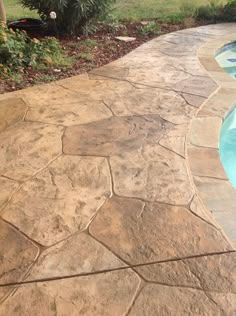 a stone walkway next to a swimming pool