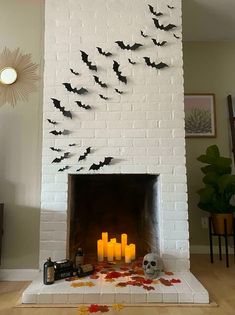 a white fireplace with candles and bats on it in front of a wall mounted fire place