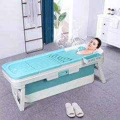 a woman laying on top of a blue and white bath tub in the middle of a room