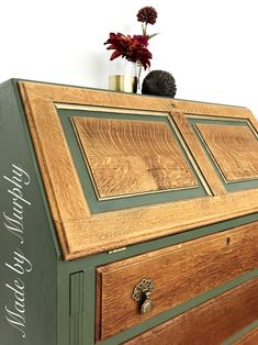 an old dresser has been painted green with gold trimmings and flowers on top