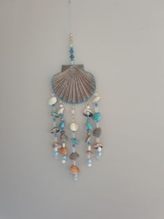 a sea shell hanging from the side of a wall with beads and shells attached to it