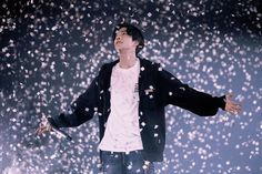 a man standing in the snow with his arms out and confetti falling around him