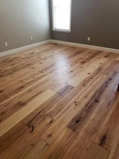 an empty room with hard wood flooring and gray walls in the corner is shown