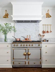 a stove top oven sitting inside of a kitchen next to two brass faucets