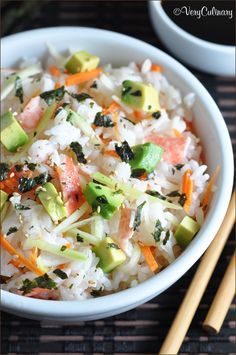 a bowl filled with rice and vegetables next to chopsticks