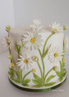 a white cake decorated with daisies and leaves