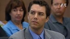 a man in a suit and tie sitting next to other people