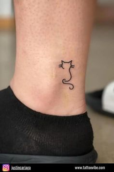 a cat tattoo on the ankle that is black and has an outline of a cat's head