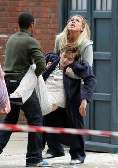 a woman is being carried by two men on the street with police tape around her