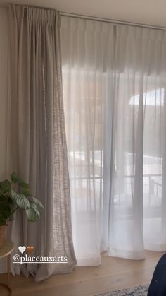 a living room with white curtains and a blue chair