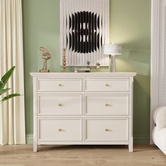 a white dresser sitting next to a chair in a room with green walls and wooden floors