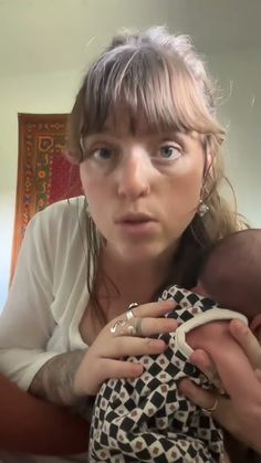 a woman holding a baby in her arms and looking at the camera with an intense look on her face