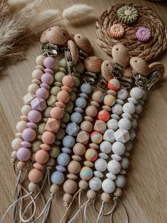 several necklaces are arranged on a table with some feathers in the background and one is made out of wood beads