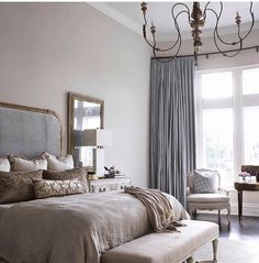 a bedroom with a large bed and a chandelier hanging from the ceiling above it