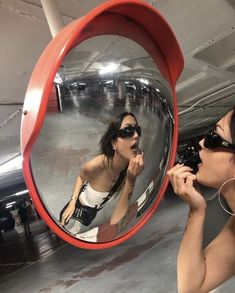 a woman is brushing her teeth in front of a mirror with an airplane behind her