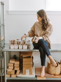 a woman sitting on top of a counter next to boxes and baskets filled with food