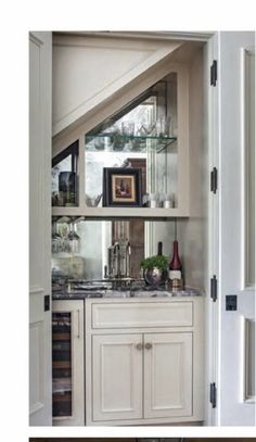 an open door leading to a kitchen with white cupboards and marble counter tops on both sides