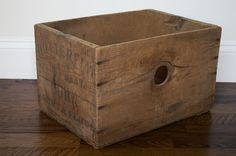 a wooden box sitting on top of a hard wood floor next to a white wall