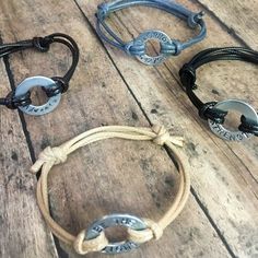 four different bracelets on a wooden table with metal clasps and rope around them