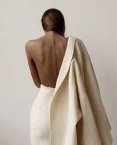 the back of a woman wearing a white dress with a shawl draped over her shoulders