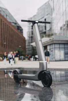 an electric scooter parked in front of a building with people walking around it