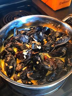 a pan filled with mussels on top of a stove