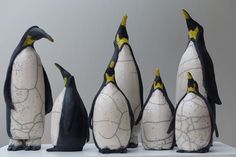 several penguins are standing in front of each other on a white surface with black and yellow accents