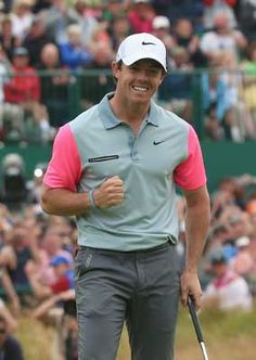 a man holding a golf club in his right hand and smiling at the camera while people watch