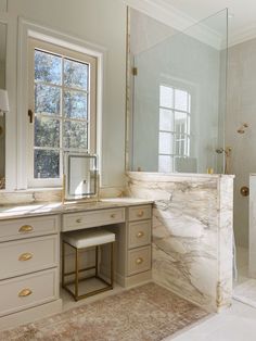 an elegant bathroom with marble counter tops and gold trim on the shower door, windows, and vanity