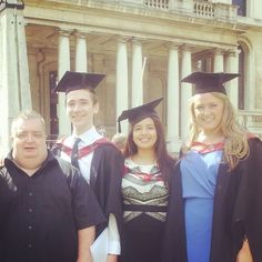 a group of people standing in front of a building wearing graduation caps and gowns