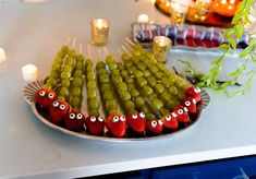 a platter filled with pickles and strawberries covered in googly eyes next to candles