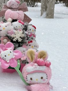 a bunch of stuffed animals sitting in the snow next to a tree with flowers on it