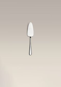 a white spatula with water dripping from it on a gray background and another spoon in the foreground