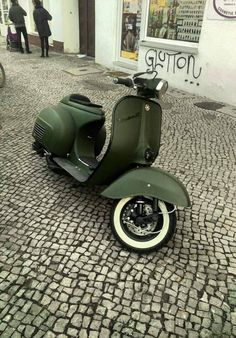 a green scooter is parked on the cobblestone street