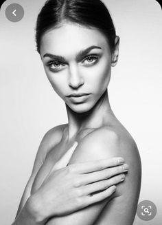 a black and white photo of a woman with her hands on her chest looking at the camera