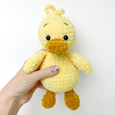 a hand holding a yellow crocheted stuffed duck