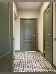 an empty hallway with green doors and tile flooring on either side of the door